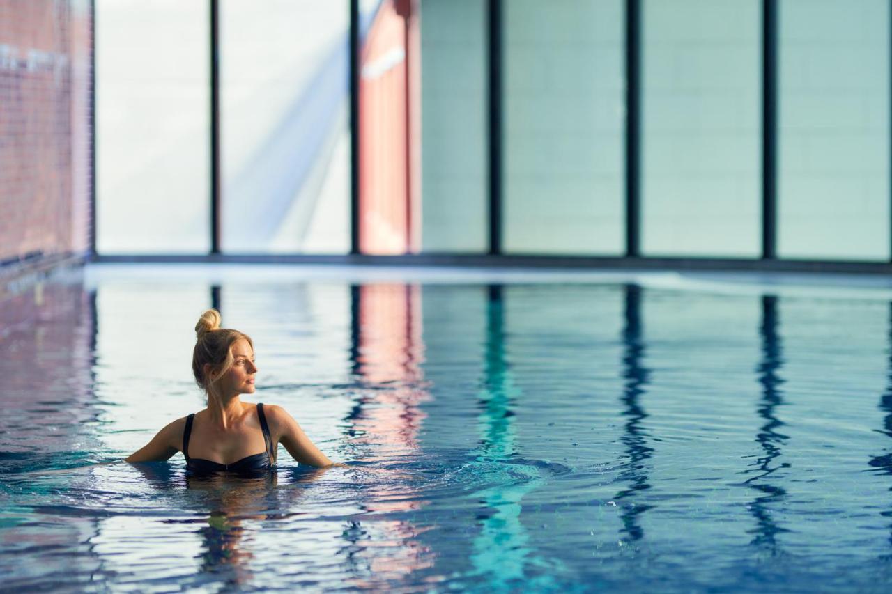 Meriton Suites Kent Street, Σίδνεϊ Εξωτερικό φωτογραφία The photo shows a woman in a swimming pool, partially submerged in water. She has a graceful posture and is looking thoughtfully to the side. The pool has a modern, serene atmosphere, with large windows that allow natural light to flood the space. Th